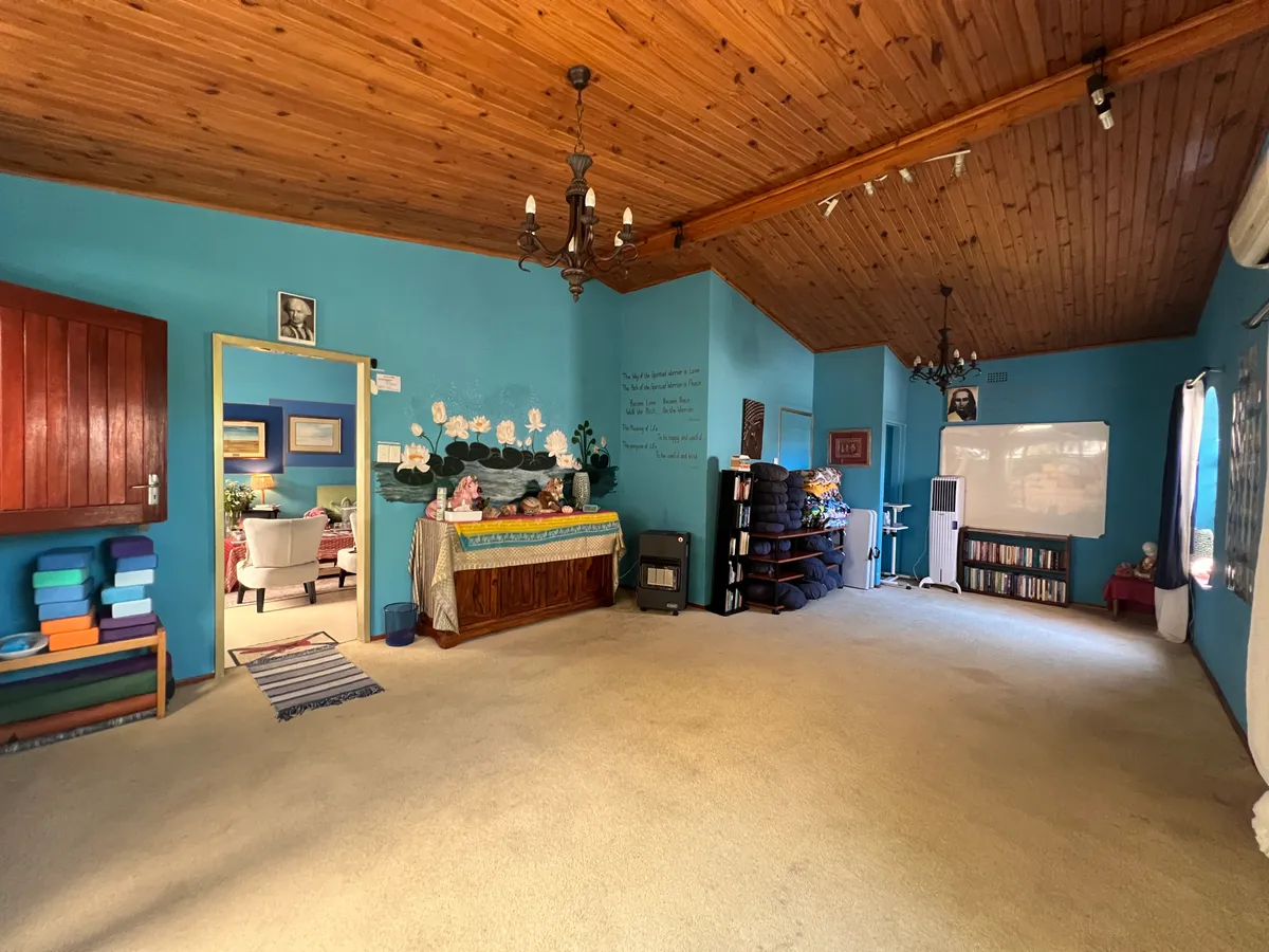 The meditation room: turquoise walls, a lotus mural above an altar table, stacked cushions and a bookshelf