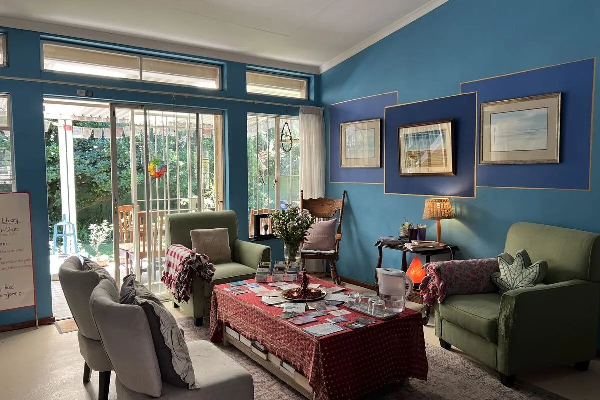 The reception room: blue walls, armchairs, a low table and glass doors to the garden