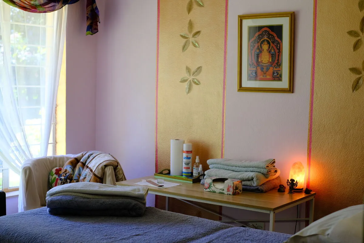 A treatment room with a couch, folded towels and a lit candle