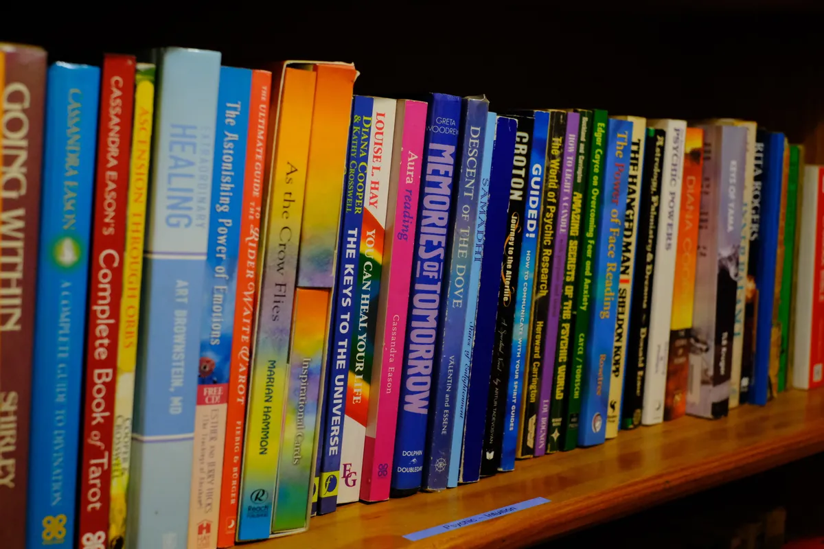 A shelf of books with brightly coloured spines, from tarot to healing and prophecy